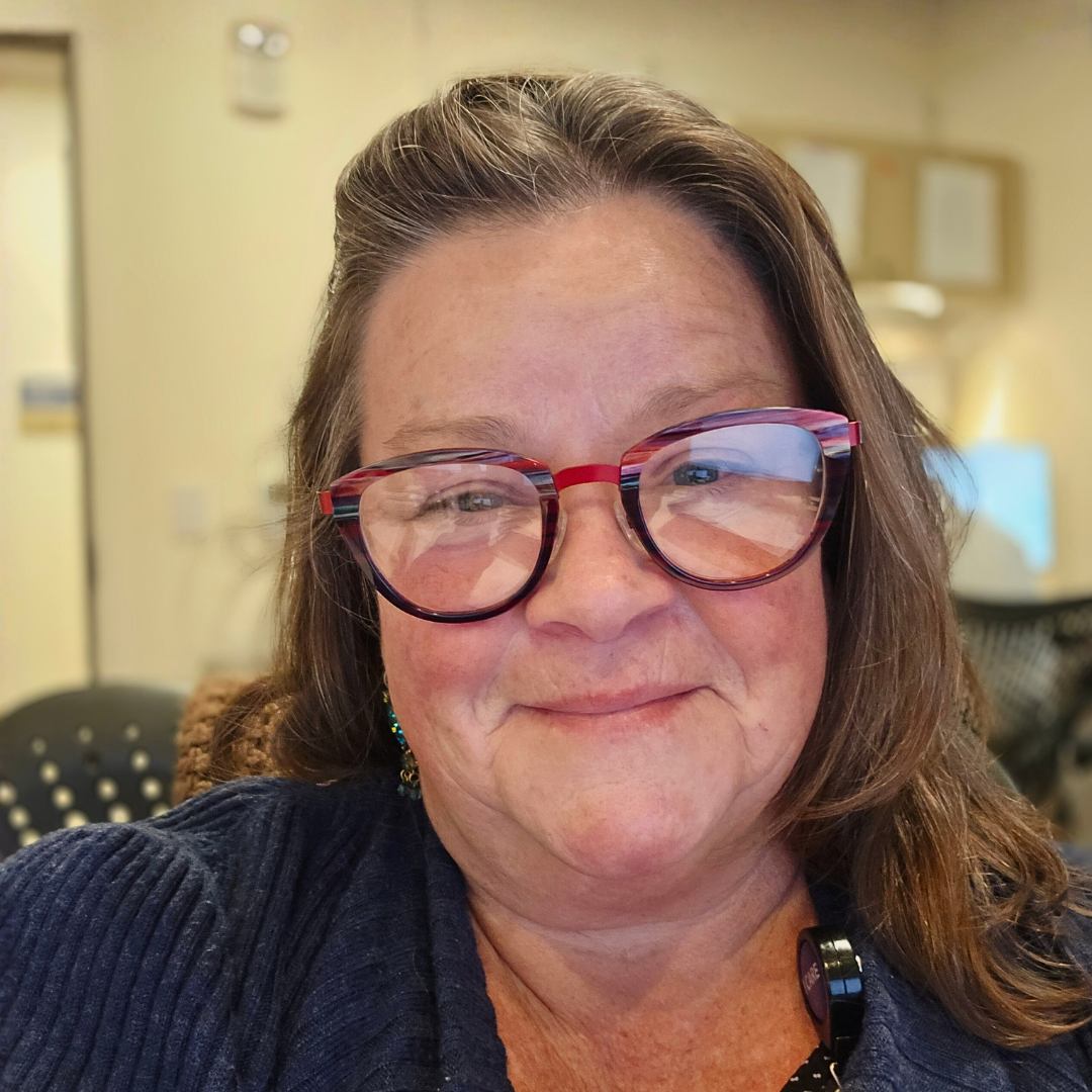 Woman with red glasses smiling indoors