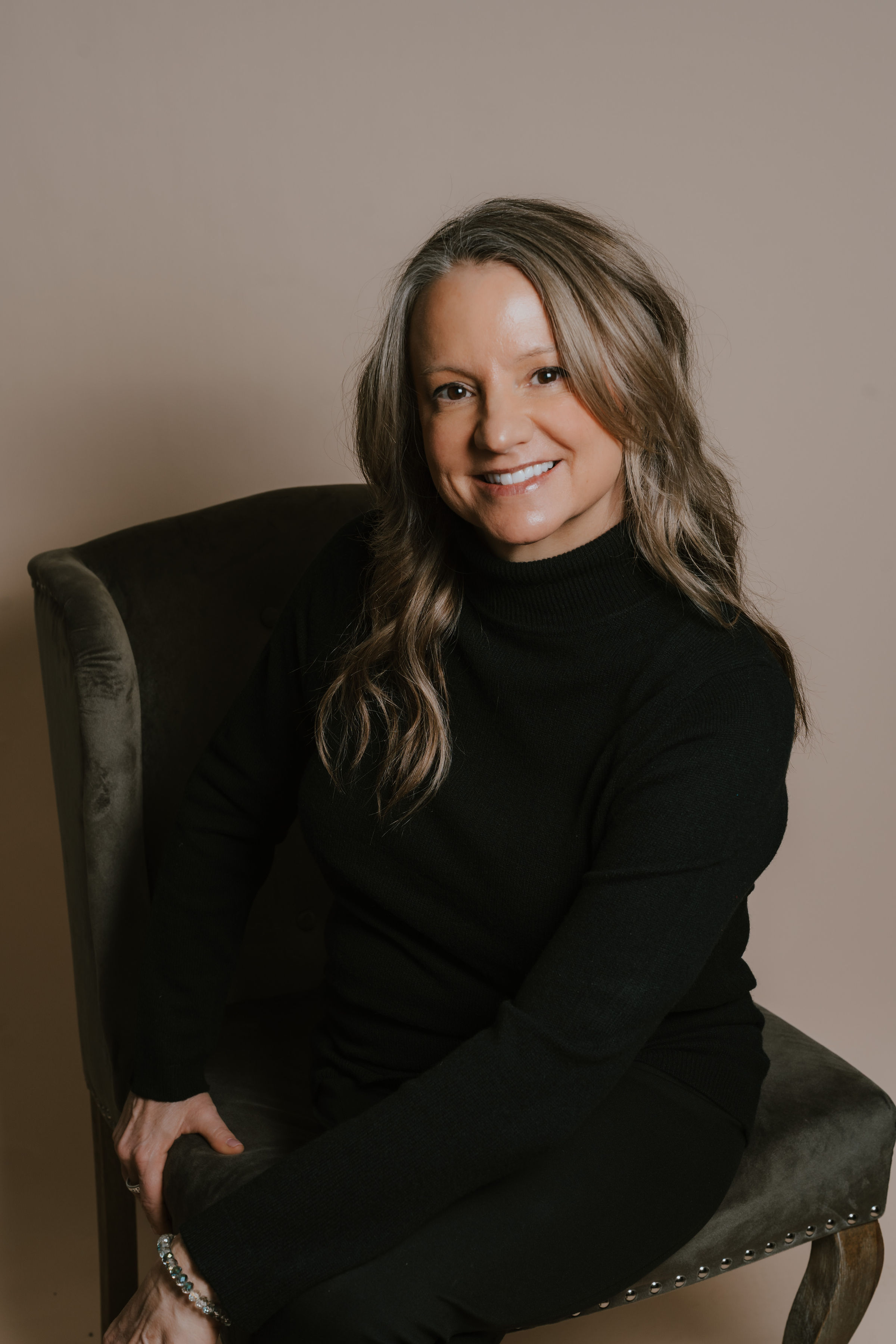 Smiling woman seated in dark chair