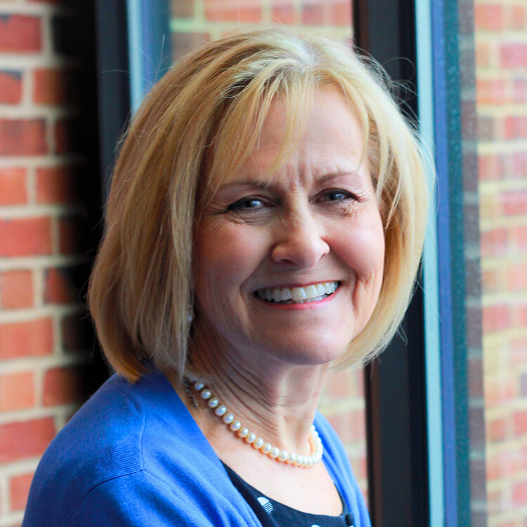 Smiling woman wearing blue cardigan and pearls