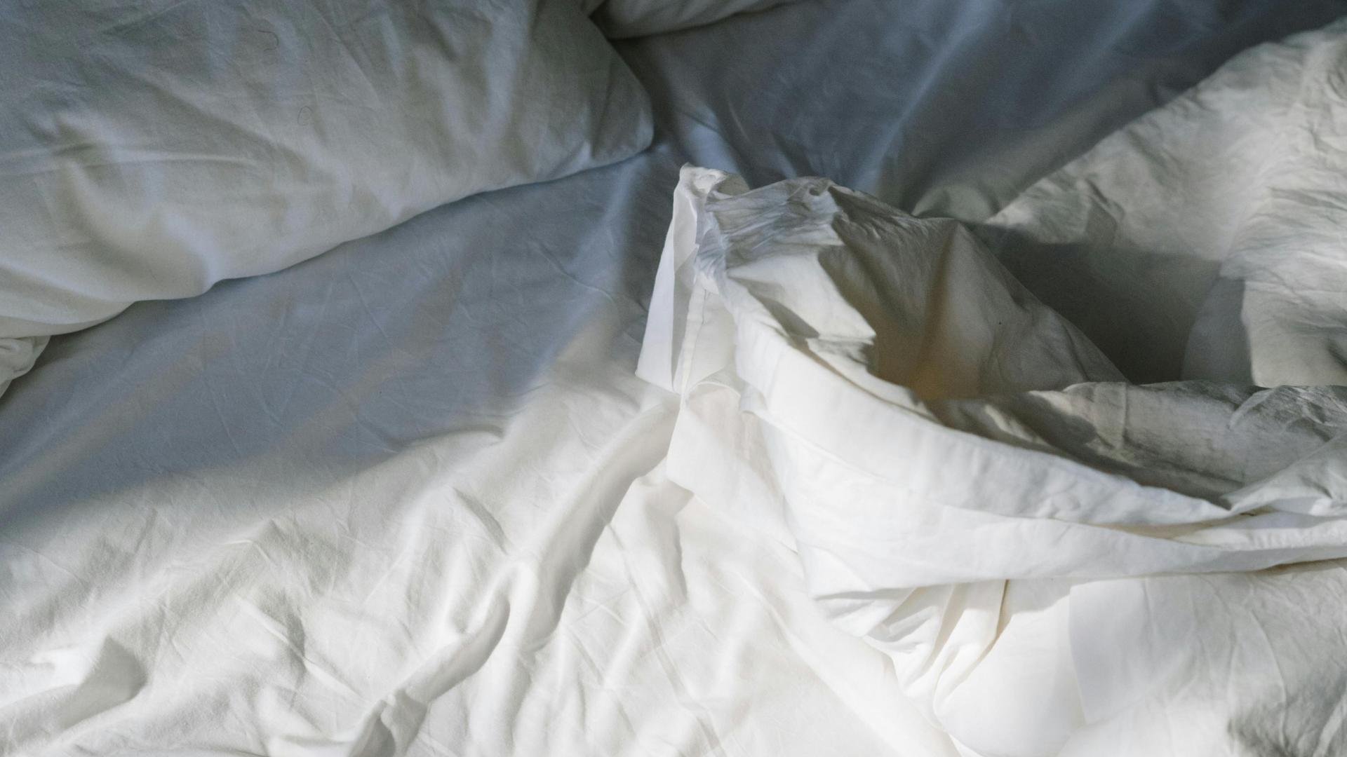 Unmade bed with rumpled sheets and pillows