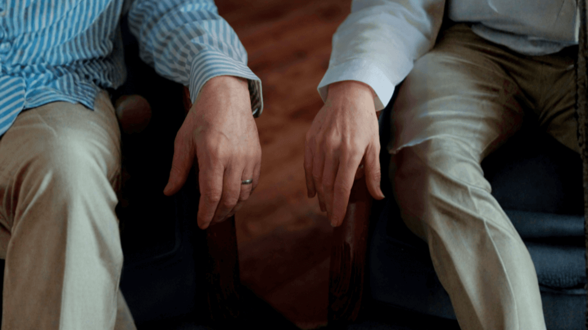 Two older adults’ hands rest side by side