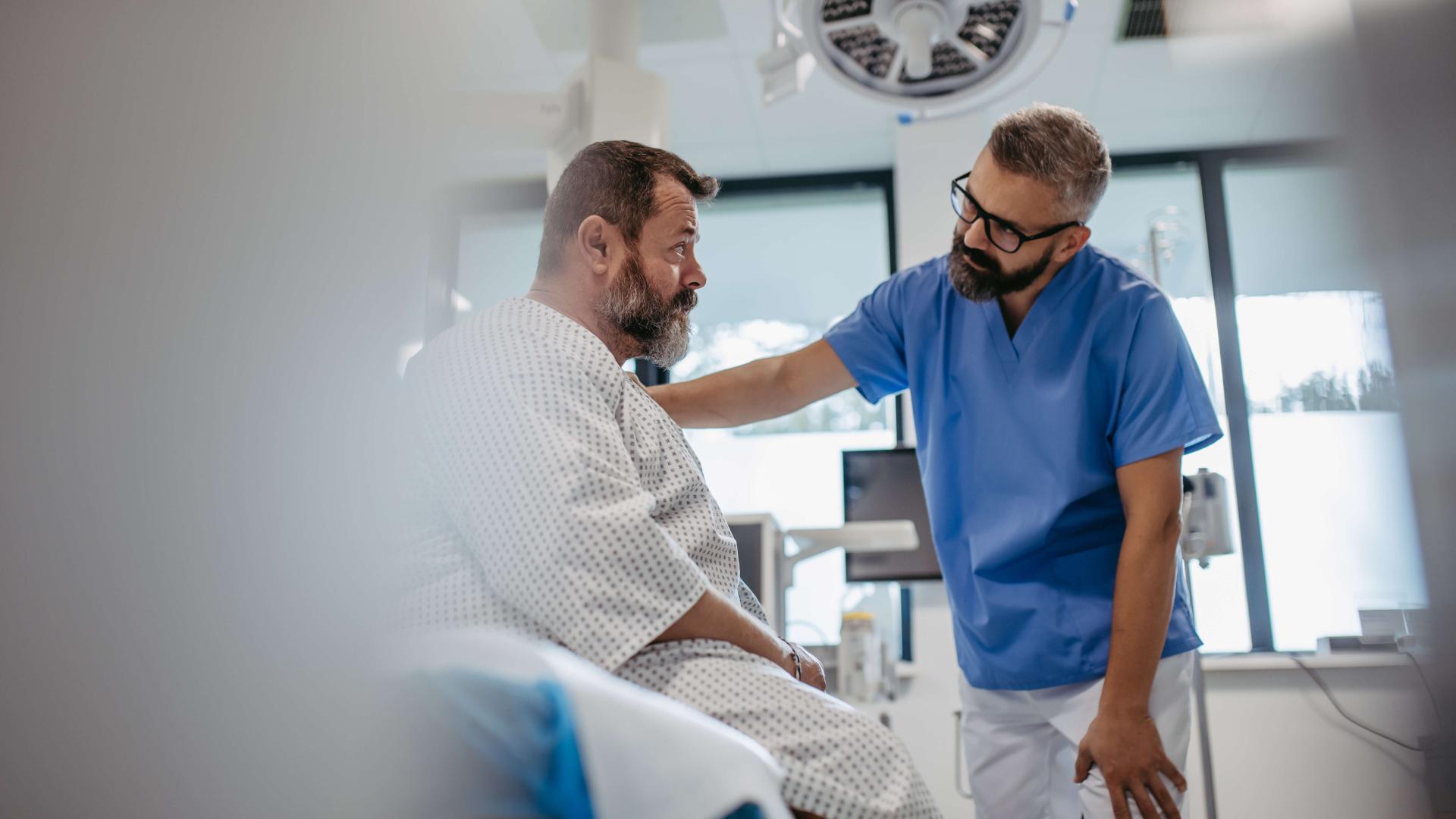 Healthcare worker speaks with patient in hospital room