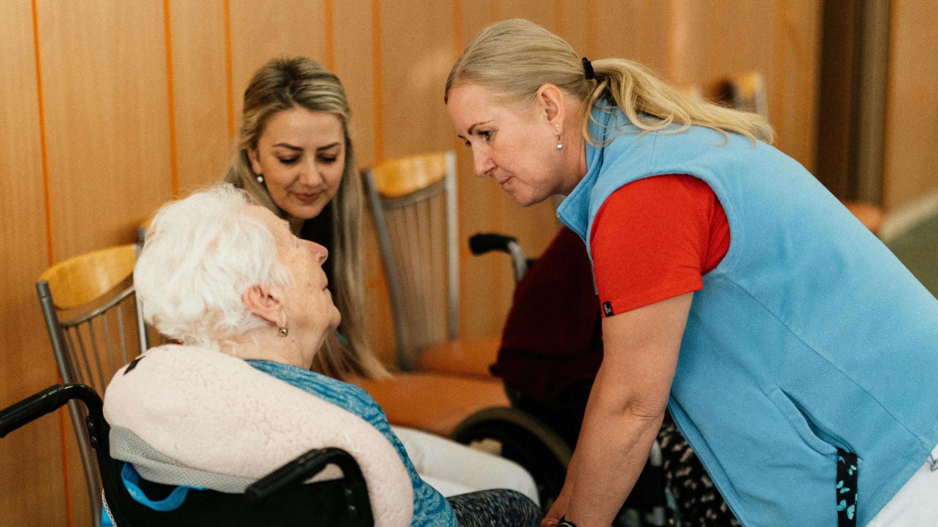 Caregiver talking to older adult in wheelchair