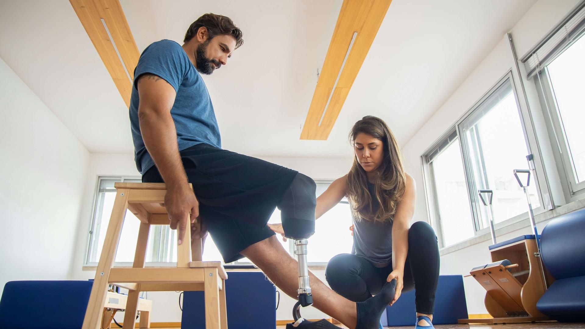 Physical therapist assisting patient with prosthetic leg