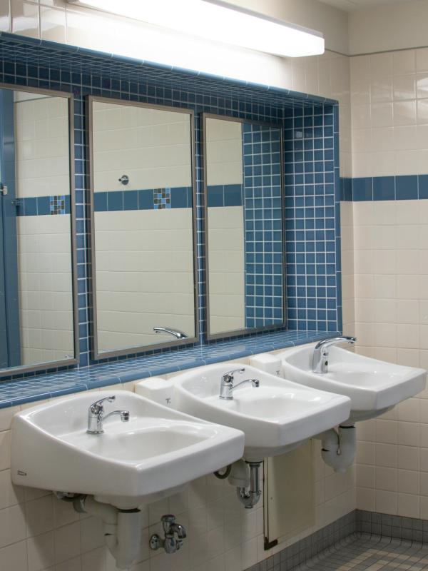 Clean, empty public restroom with three sinks, mirrors, and tiled walls, suggesting a private, quiet space where someone might step away briefly to regroup or ground themselves during a work shift.