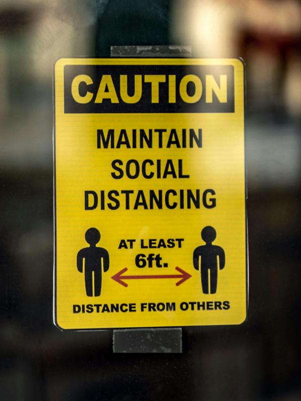 Yellow sign reads “Maintain Social Distancing”