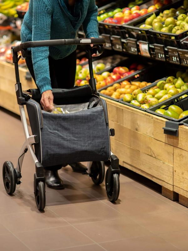 Person using walker reaching for groceries in aisle