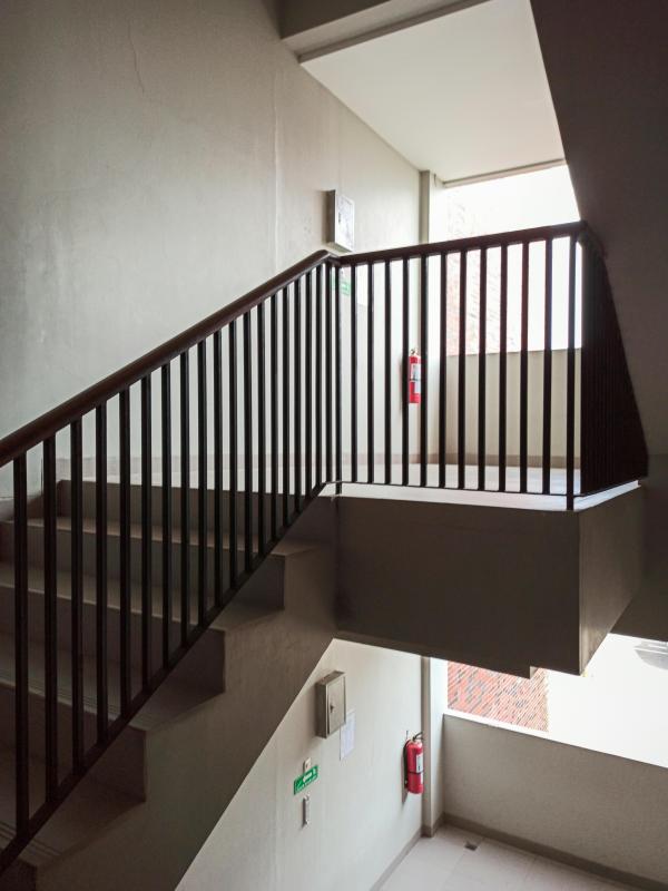 Empty hospital stairwell with railings and natural light, suggesting a quiet, low-traffic space where staff might pause briefly during a shift.