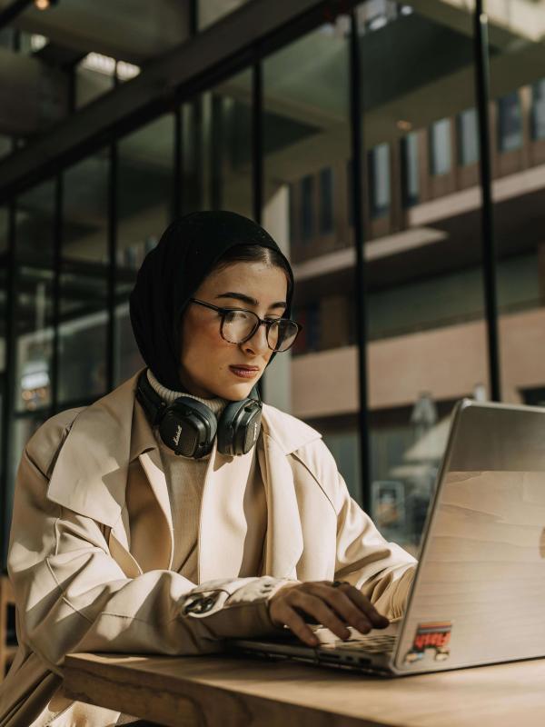Person with headscarf working on laptop.