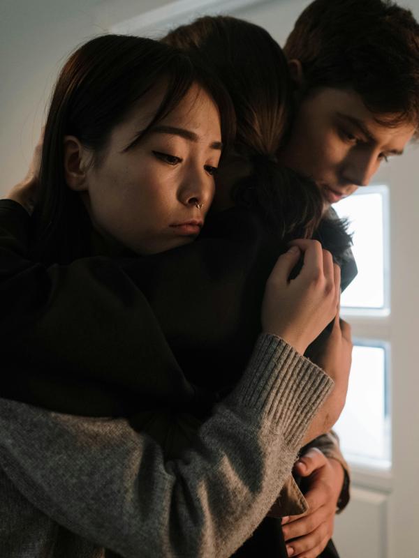 Three people embrace in quiet support