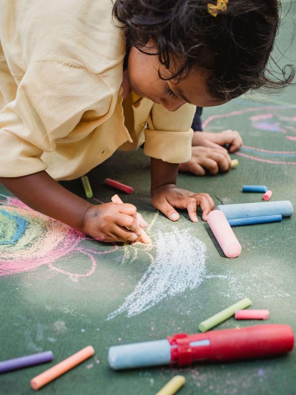 Child drawing chalk hearts outdoors