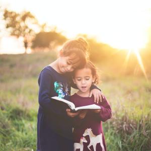 A photo of two girls hugging with the sun setting in the background