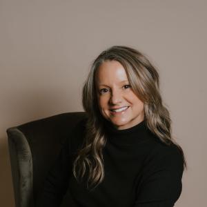 Smiling woman seated in dark chair