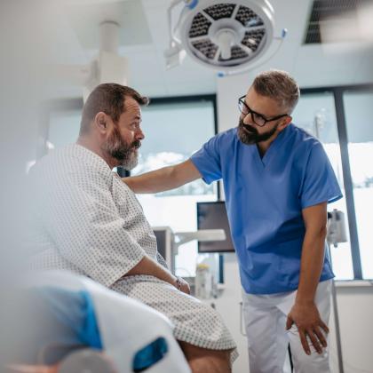 Healthcare worker speaks with patient in hospital room